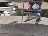 reflection of a man on a car door with a skateboard in front of him