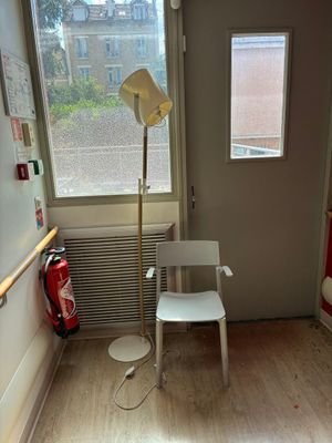 une chaise blanche dans un coin de la pièce, près d'une fenêtre