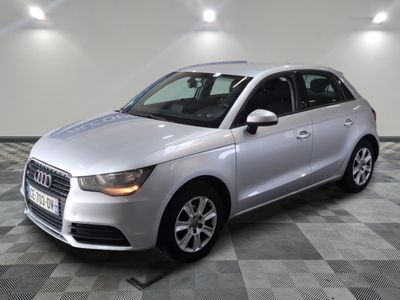 L'Audi argentée est garée dans une grande pièce au sol carrelé en damier.