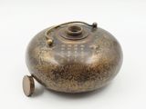 a brown and gold tea pot on a white surface
