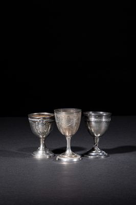 three silver goblets sitting on a table with a black background