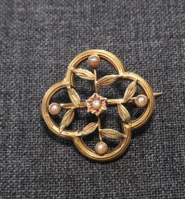 Gros plan sur une broche en or ornée de perles