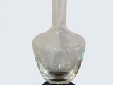 a clear glass vase with a blue base on a white surface