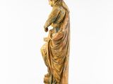 a wooden statue of a woman sitting on a stool