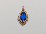 a close up of a blue stone pendant on a white surface