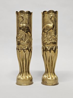 paire de vases dorés sur fond blanc, avec un oiseau représenté sur l'un des vases