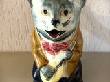 une figurine de chat portant un nœud papillon et jouant de la guitare