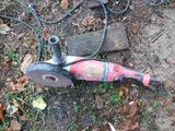 un sèche-cheveux rouge et noir posé par terre à côté d'un morceau de bois