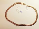 a close up of a gold chain bracelet on a white surface