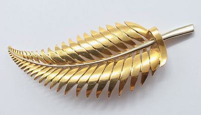 une image représentant une broche en feuille d'or posée sur une surface blanche