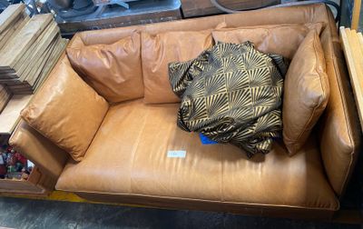 a brown leather couch with a pillow on top of it