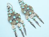 a pair of earrings with turquoise beads and silver spikes on them