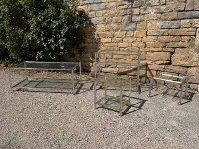 three glass tables and two chairs in front of a stone wall