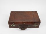 une vieille valise en cuir marron posée sur une surface blanche