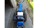 a small blue tractor parked on the side of the road