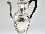 an antique silver tea pot with a black handle on a white surface
