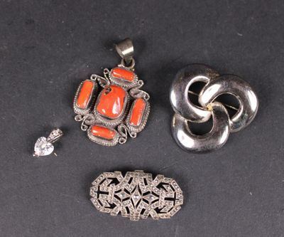 trois bijoux en argent et en corail posés sur un fond noir