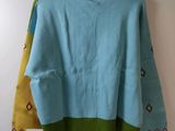 a blue sweater with yellow and green trims hanging on a hanger