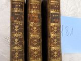 trois vieux livres posés sur une table, à côté d'une feuille de papier