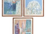 three framed paintings of a city and a body of water