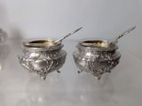 two silver bowls with spoons on a table