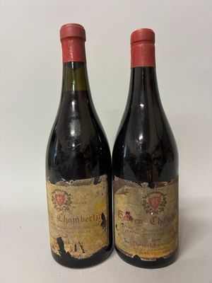 two bottles of red wine sitting on top of a white table