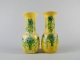 pair of yellow vases with blue flowers on them against a white background