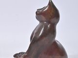 a small statue of a cat sitting on a white surface