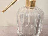 a clear glass bottle with a gold handle on a table