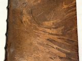 un vieux livre en cuir marron posé sur une table blanche
