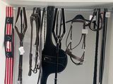 une photo d'une sellerie contenant de nombreux équipements d'équitation