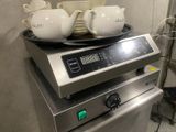 a tea pot on top of a stove with tea cups on it