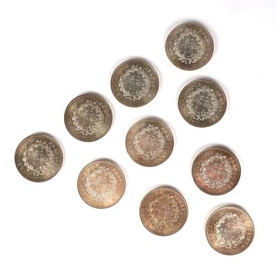 six types de pièces différents disposés en triangle sur une surface blanche