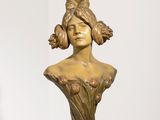 sculpture représentant la tête d'une femme, posée sur un socle devant un mur blanc