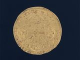 une vieille pièce d'or sur laquelle figure une croix, sur fond noir