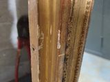a close up of a gold frame with a red chair in the background