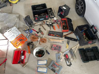 de nombreux outils qui traînent par terre à côté d'une voiture