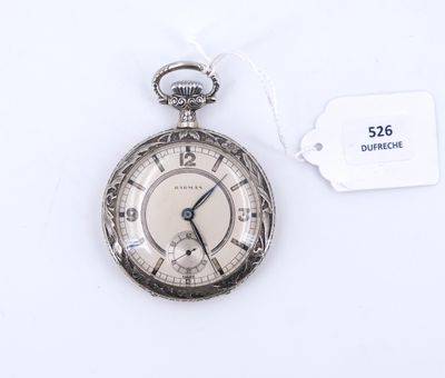 une montre de poche en argent posée sur une surface blanche, avec une étiquette de prix