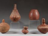 Plusieurs pièces de poterie sont posées sur un support, sur une surface grise.