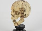 a close up of a wooden skull on a black stand