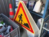 a yellow caution sign sitting on the floor next to a pile of other items