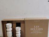 trois bougies blanches posées les unes à côté des autres dans une boîte