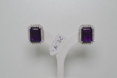 une paire de boucles d'oreilles en améthorate et diamants, présentée sur un socle blanc