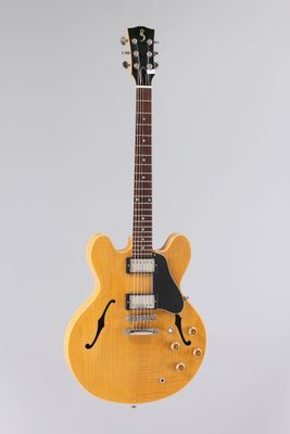 une guitare électrique jaune accrochée à un mur sur fond blanc