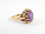 gros plan d'une bague en or avec une pierre violette