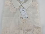 La chemise est blanche et est ornée d'un motif floral.