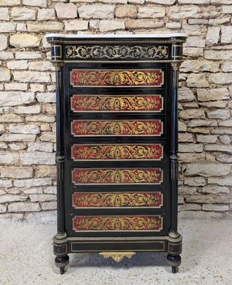 a black and gold chest of drawers against a brick wall