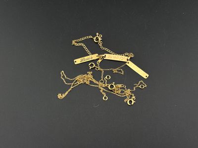 un gros plan sur un lot de colliers en or posés sur une surface noire