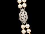 a close up of a necklace with pearls and diamonds on a black background