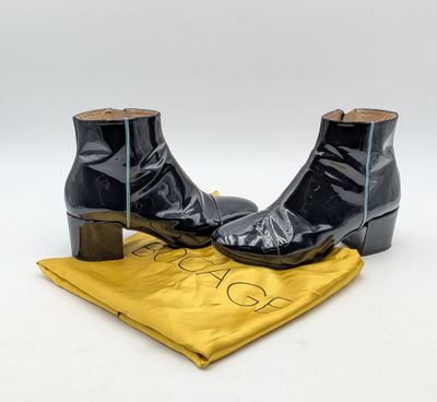 une paire de bottines en cuir noir posées sur un tissu jaune